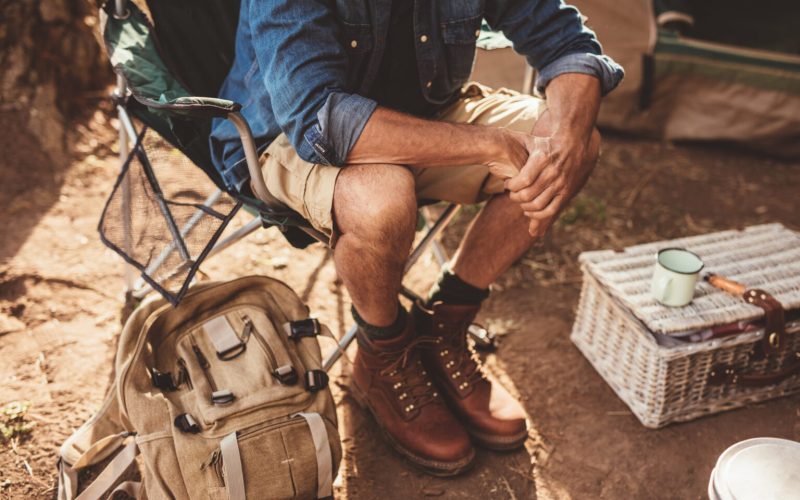 Close up shot of mature man sitting on a chair. Man relaxing at campsite, focus on hands.